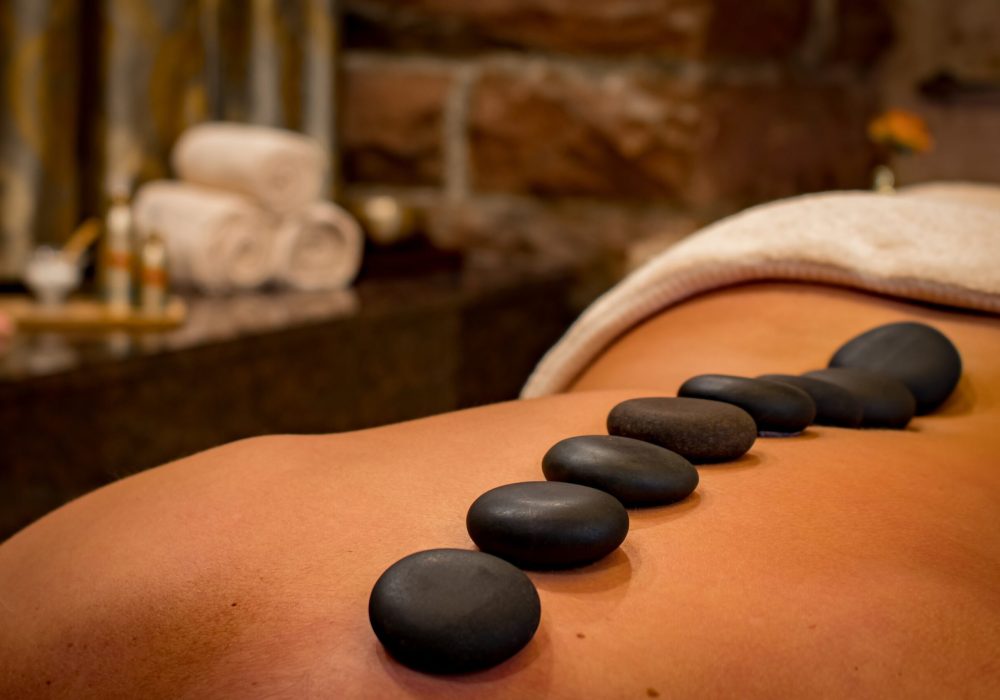Eine Frau liegt auf einem Massage Tisch und bekommt eine Hot Stone Behandlung